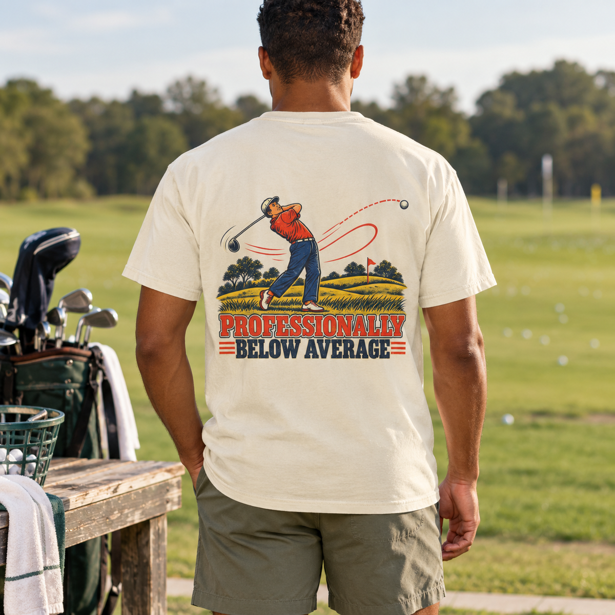 Professionally Below Average tee in Ivory, back print shown on a model in a golf-course lifestyle mockup